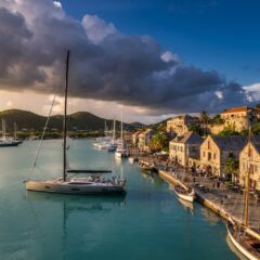 Vista panorâmica do porto histórico de Nelson's Dockyard em Antígua e Barbuda com barcos ancorados em águas cristalinas.